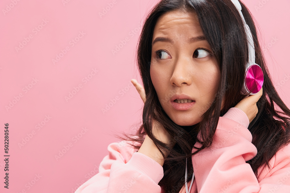 Closeup portrait of shocked cute Asian student young lady in pink hoodie sweatshirt with cute headphones posing isolated on over pink studio background. Good offer. Sound streaming platform ad concept Closeup portrait of shocked cute Asian student young lady in pink hoodie sweatshirt with cute headphones posing isolated on over pink studio background. Good offer. Sound streaming platform ad concept