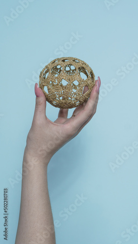 female hand on a blue background holds a ball of yarn for knitting close-up
