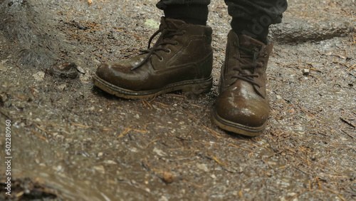 Close-up of traveler in boots standing on ground. Stock footage. Hiking boots can withstand extreme wet and muddy walk in rainy weather