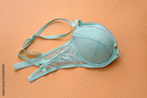 Green bra with lace on a beige background. Bra pale blue with pushap folded in two. Beautiful lingerie.