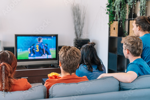 friends watching a game of football on television in their living room. copy space