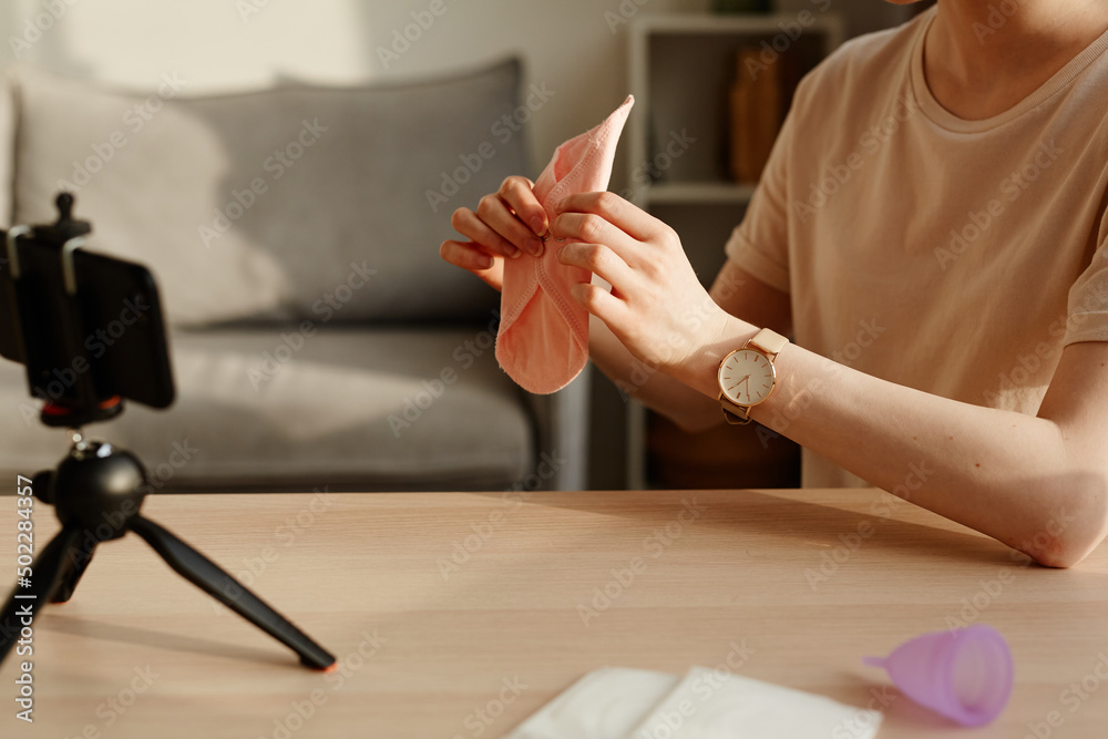 Obraz premium Minimal closeup of young woman holding reusable pad to camera and filming educational video on feminine products