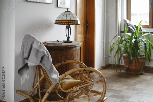 Bilde på lerret Old fashion wicker rocking chair with blanket in cozy house, lamp on wooden cabinet