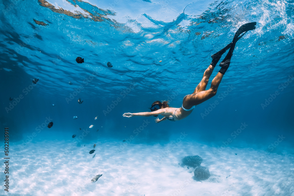 Beauty freediver girl dive with fins in blue tropical ocean with fishes