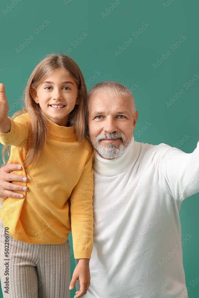 Little girl with her grandfather on green background Little girl with her grandfather on green background