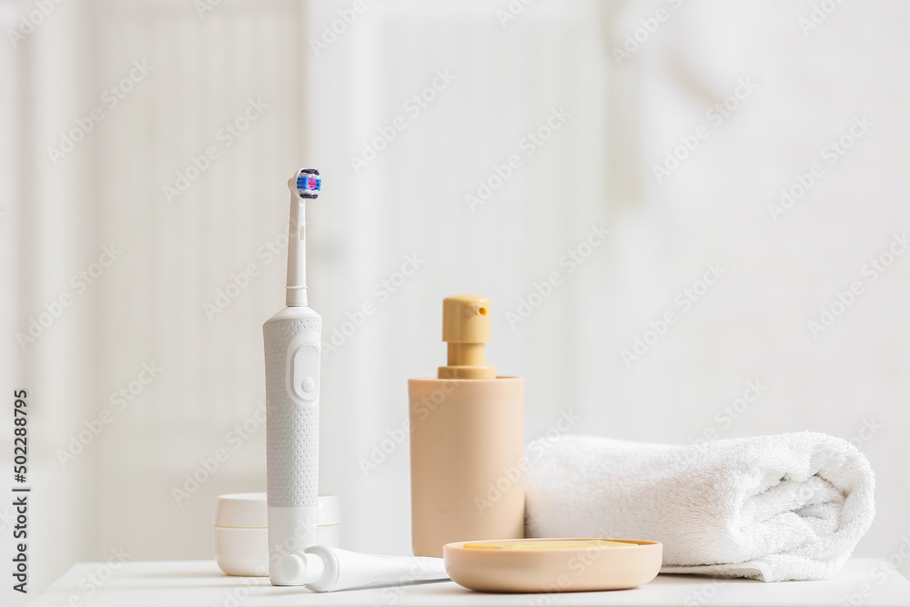 Electric toothbrush, cosmetic products and rolled towel on table