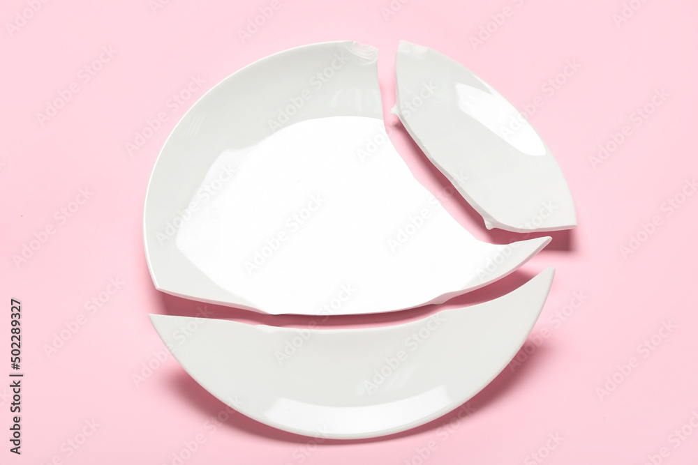 Broken ceramic plate on pink background