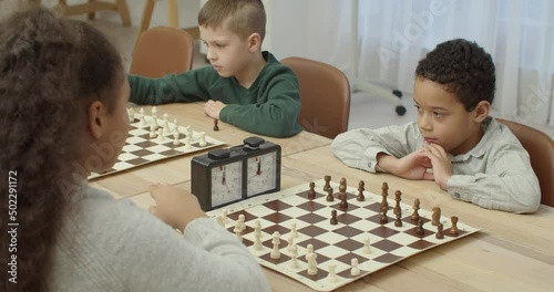Little children playing chess during tournament in club