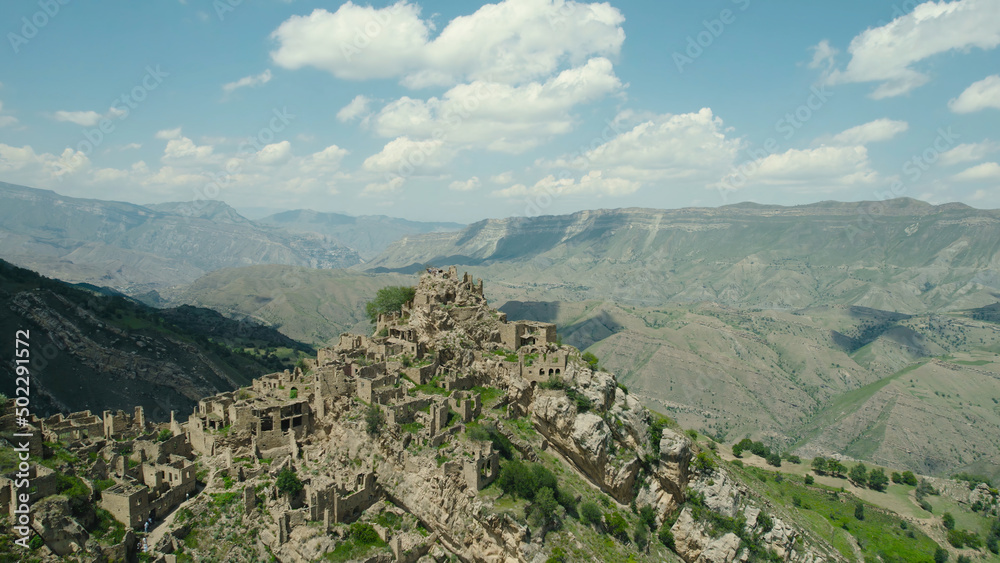 Ancient stone city on rock on background of mountains. Action. Amazing settlement of rock houses on top of mountain. Attraction of Dagestan - village of ghost in mountains