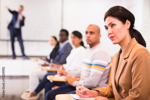 Portrait of asian woman attending business training  listening with interest to speaker