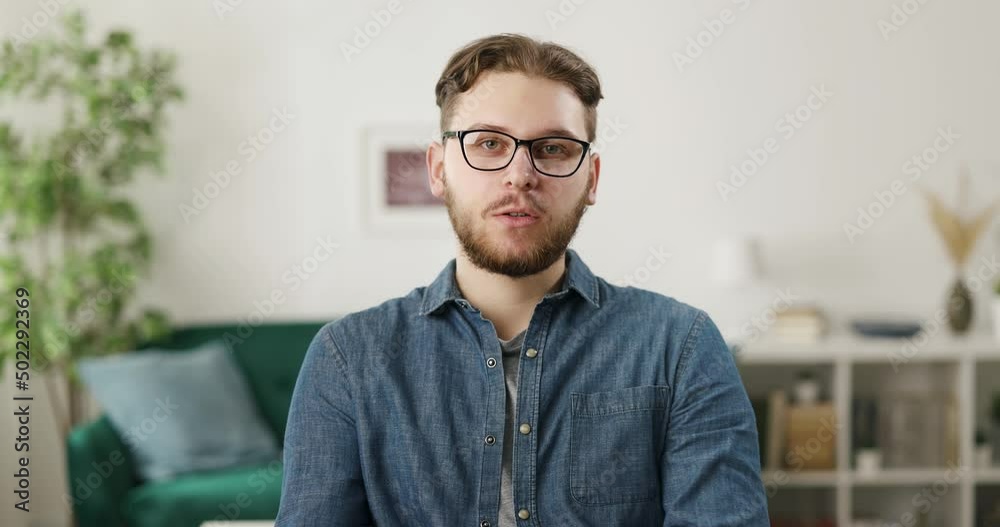 First person view of caucasian bearded man sitting on comfy couch, talking and gesturing confidently. Concept of people and online communication. First person view of caucasian bearded man sitting on comfy couch, talking and gesturing confidently. Concept of people and online communication.