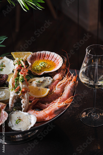 Baked oysters, crab with sauce and a slice of lemon. A glass of white wine with a seafood platter