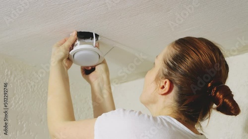 a woman changes a ceiling lamp