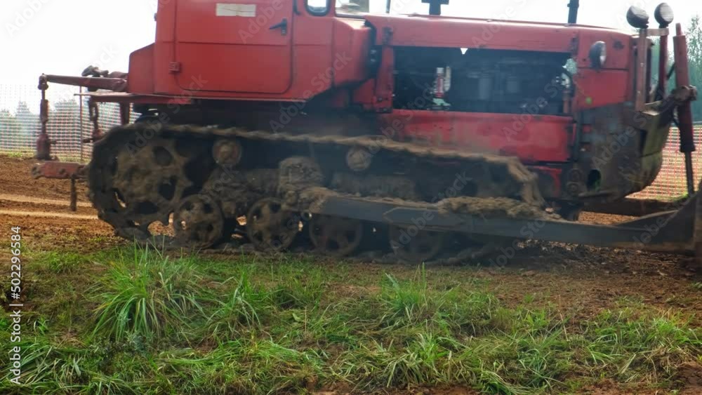A bulldozer crawler tractor with a metal bucket is passing by. A bulldozer crawler tractor with a metal bucket is passing by.