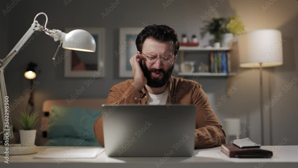 Pain and itching in ear. Bearded male computer user scratches and touches his ear. Freelancer at workplace experiencing otitis media and inflammation in right ear Pain and itching in ear. Bearded male computer user scratches and touches his ear. Freelancer at workplace experiencing otitis media and inflammation in right ear