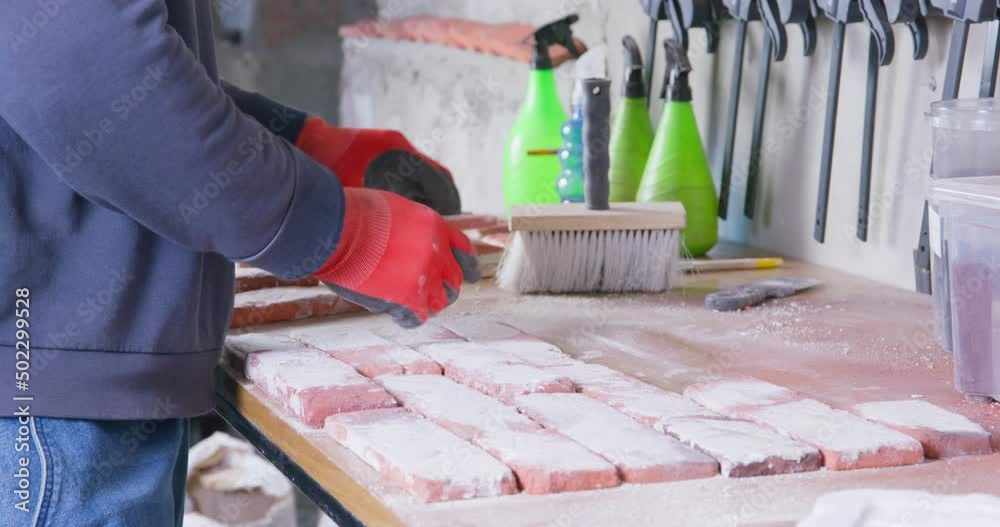 Craftsman makes tiles of antique style cast bricks for building facades and interiors. Man in rubber gloves busy with preparation of craft bricks closeup Craftsman makes tiles of antique style cast bricks for building facades and interiors. Man in rubber gloves busy with preparation of craft bricks closeup