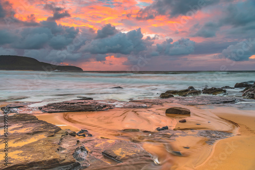 Soft sunrise seascape with rocks and rain clouds
