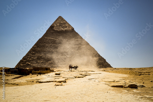 Horses and camels kick up dust in front of the Pyramid of Khafre at the Great Pyramids of Giza, Egypt.