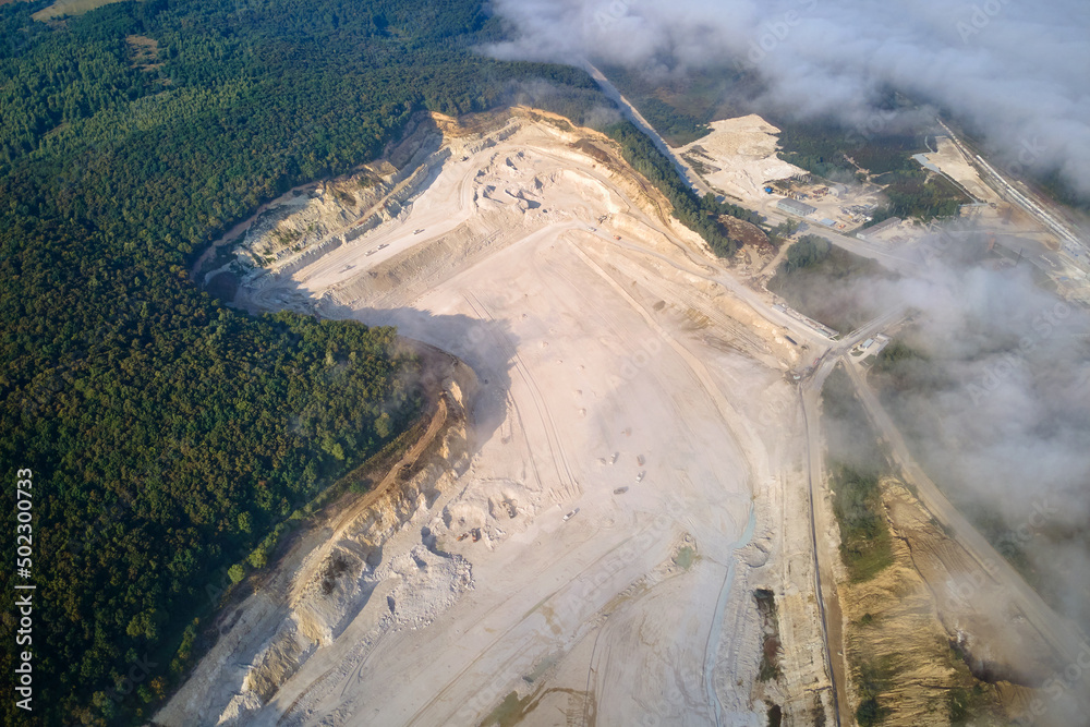 Aerial view of open pit mining of limestone materials for construction industry with excavators and dump trucks