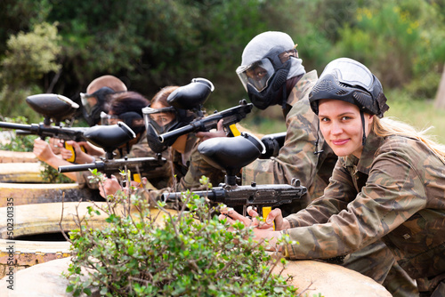 Portrait of team of happy adult people playing on paintball battlefield outdoor