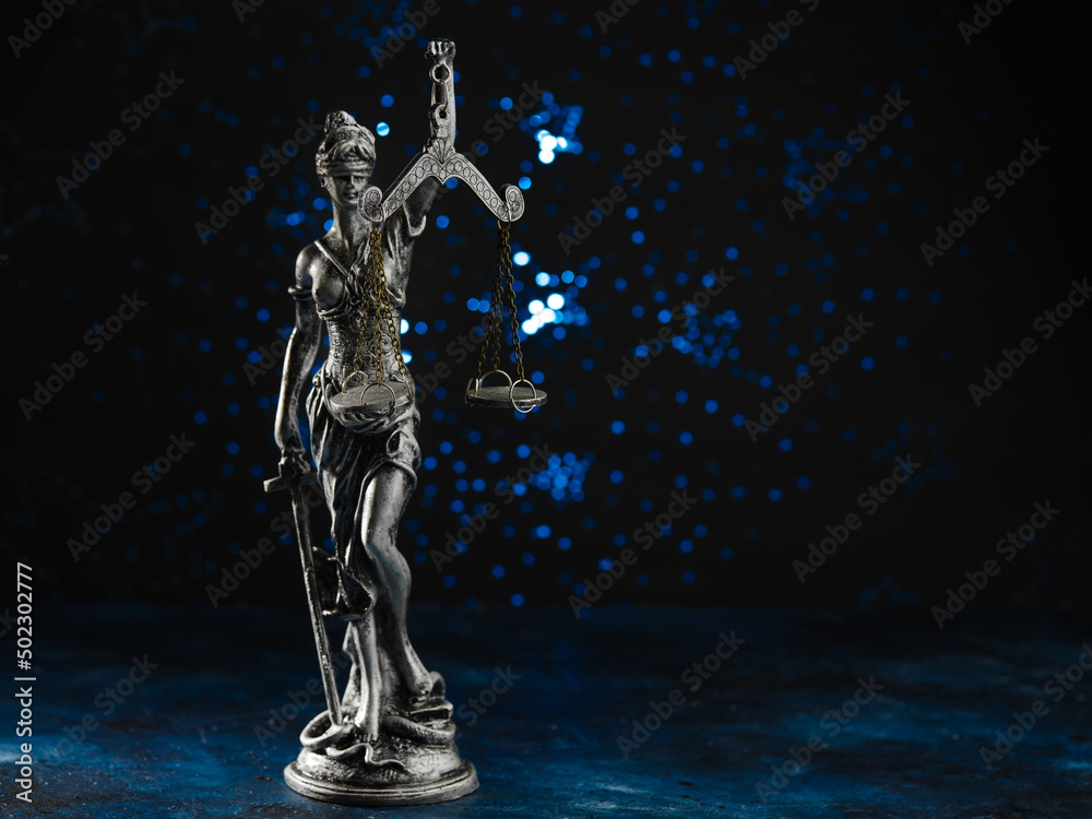 Bronze statuette of the goddess of justice Themis on a dark blue background. Court, advocacy, democracy, rule of law, justice. There are no people in the photo. Minimalism.
