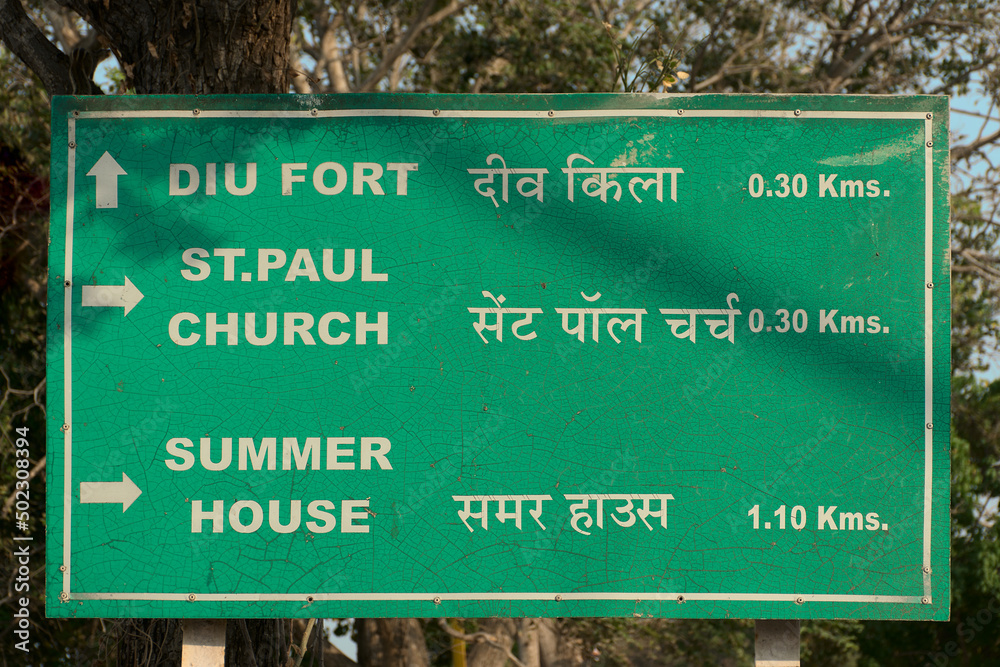 Green colored signpost showing directions to popular tourist places located in the town of Diu, India