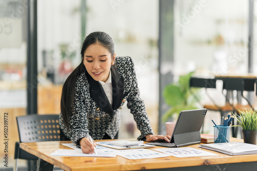Portrait of Asian young female working on laptop and financial report at office.