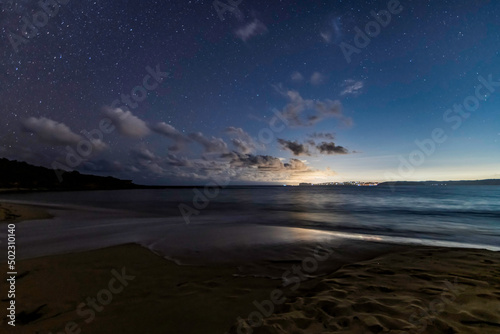 The night sky at the beach and the city lights in the distance