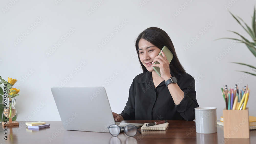 Charming woman having conversation with mobile phone and using laptop in cafe. Charming woman having conversation with mobile phone and using laptop in cafe.