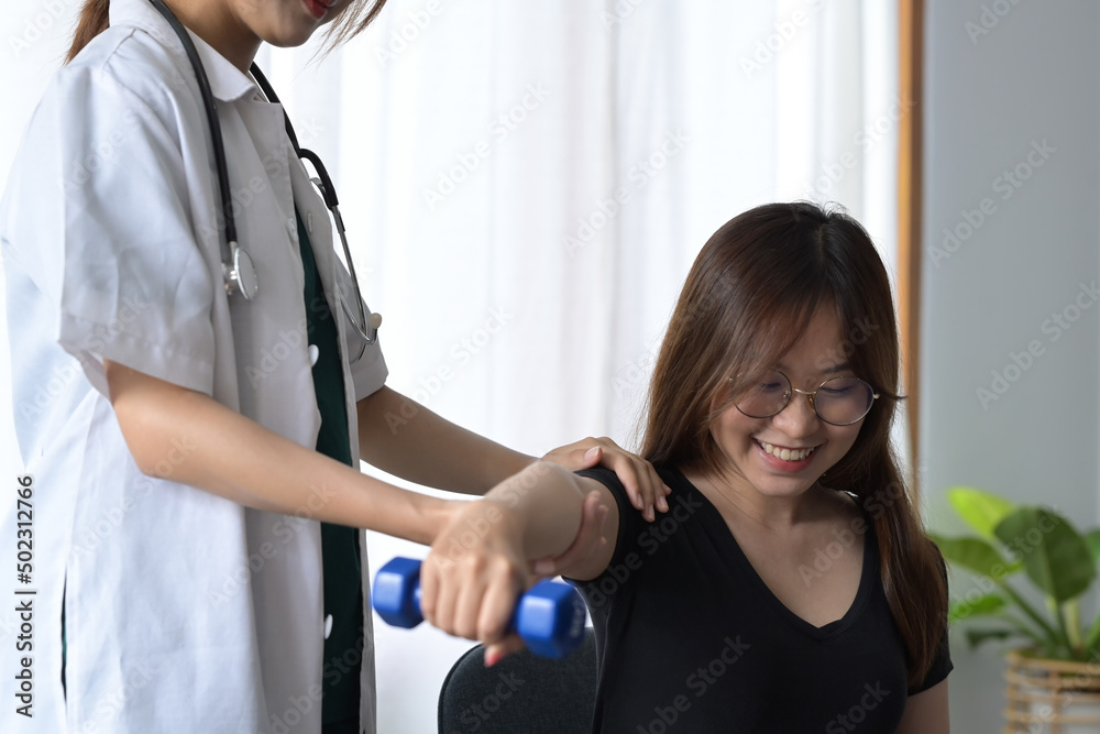 Female physiotherapist giving exercise with dumbbell treatment about arm and shoulder of female patient. Physical therapy concept. Female physiotherapist giving exercise with dumbbell treatment about arm and shoulder of female patient. Physical therapy concept.