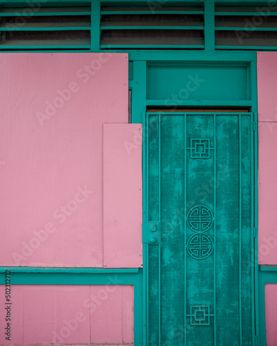 Foto Pink and Teal Background of an Old Building and an Iron Door.