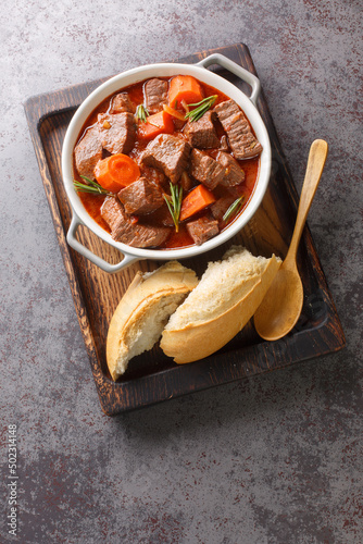 Daube Provencal French stew beef with vegetables is slow simmered to tenderness closeup in the wooden tray on the table. Vertical top view from above