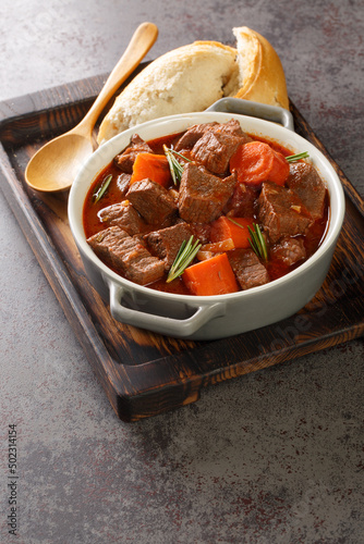 Daube Provencal French stew beef with vegetables is slow simmered to tenderness closeup in the wooden tray on the table. Vertical
