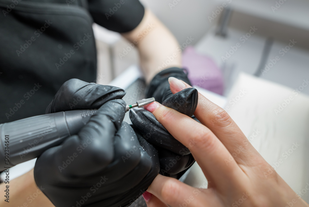 A woman uses an electric drill nail file in a beauty salon.