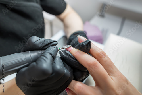 A woman uses an electric drill nail file in a beauty salon.