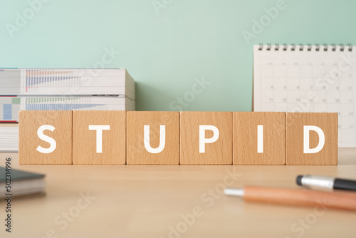 「STUPID」と書かれた積み木が置かれたデスク