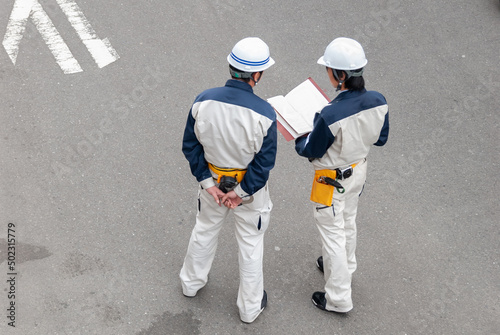 書類を見る作業服姿の２人の男性作業員