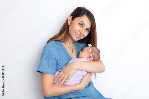 Beautiful young mother with a newborn daughter in a diaper on a white background. Motherhood. Tenderness. Space for text.