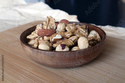 A mixture of nuts in a wooden bowl on a wooden board. Dried nuts.