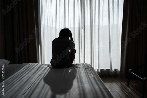 Fototapet Lonely young man feeling depressed and stressed sitting in the dark bedroom, Neg