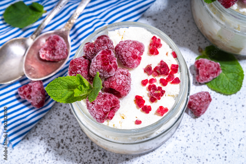 Overnight cheesecake oatmeal. Cheesecake morning breakfast layered parfafait dessert with homemade cottage cheese, mascarpone, oats and fresh raspberries, on sunny white concrete background copy space Overnight cheesecake oatmeal. Cheesecake morning breakfast layered parfafait dessert with homemade cottage cheese, mascarpone, oats and fresh raspberries, on sunny white concrete background copy space
