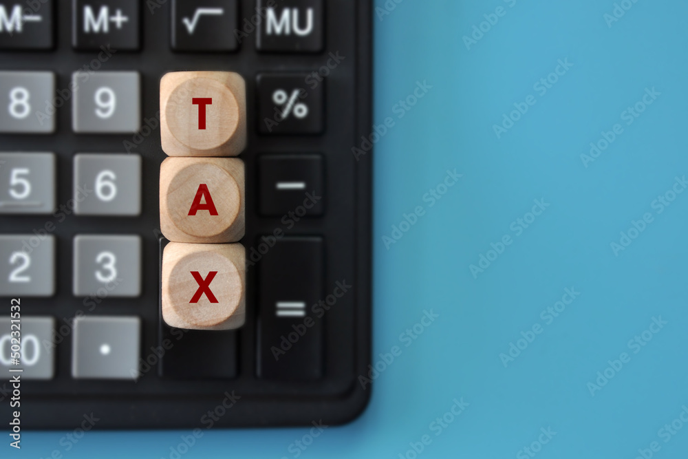Wooden cubes with the inscription: tax and calculator nearby. Tax Reporting symbol Wooden cubes with the inscription: tax and calculator nearby. Tax Reporting symbol