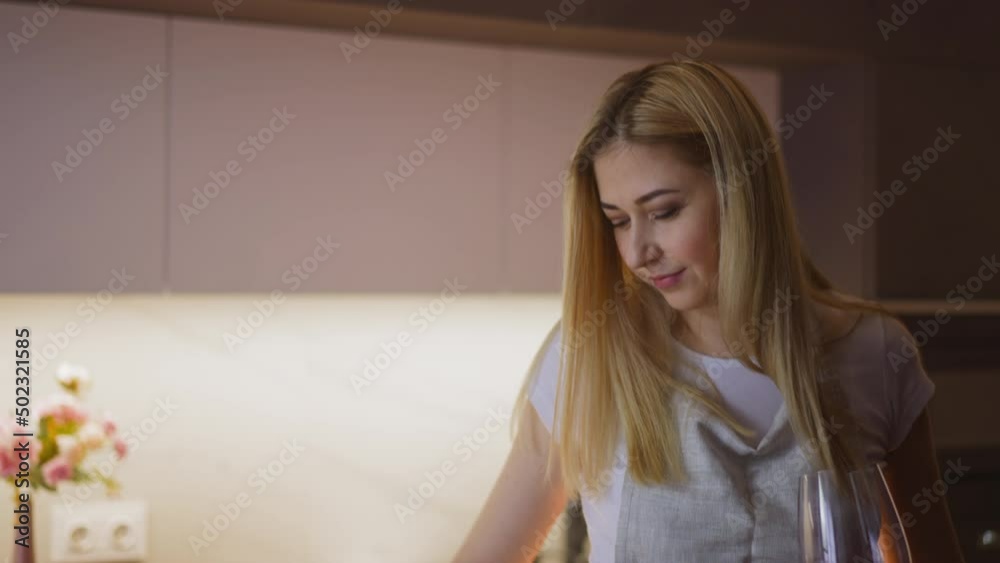 Cheerful lady in casual clothes with wineglass of aged vintage wine dances cooking tasty food in light kitchen at home close view slow motion Cheerful lady in casual clothes with wineglass of aged vintage wine dances cooking tasty food in light kitchen at home close view slow motion