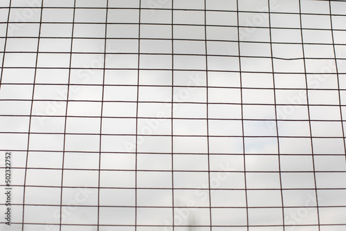 Lattice against gray sky. Steel cage.