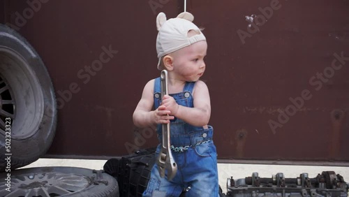 baby mechanic takes wrench and looks around closeup