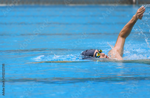 young swimmer in goggles exercising in swimming pool