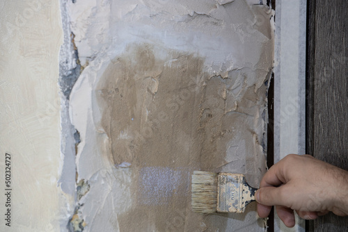The painter primes the wall with a primer. Repair and priming of the wall before applying the plaster. Painting and construction work and interior decoration.