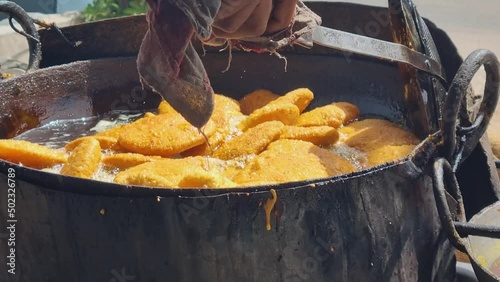 close up of shop cook deep frying many kachori in boiling oil making streetfood snack that is popular throughout rajasthan jaipur India for it's spicy flavor photo