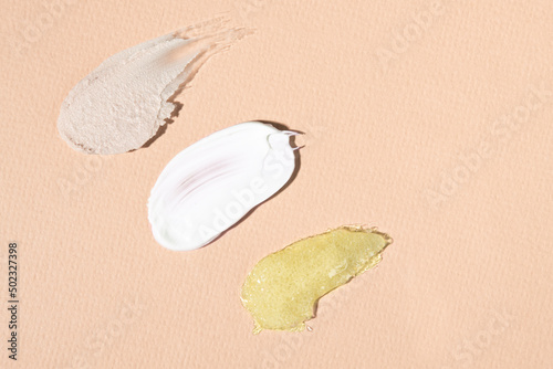 Samples of cosmetics on a beige background, body cream, scrub and clay mask. Texture close-up.