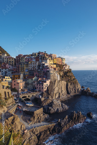 Beautiful view of rocky hills and colorful historic buildings of Manarola, tourist attraction and famous place in Liguria, Italy. Hillside over the sea at sunset.